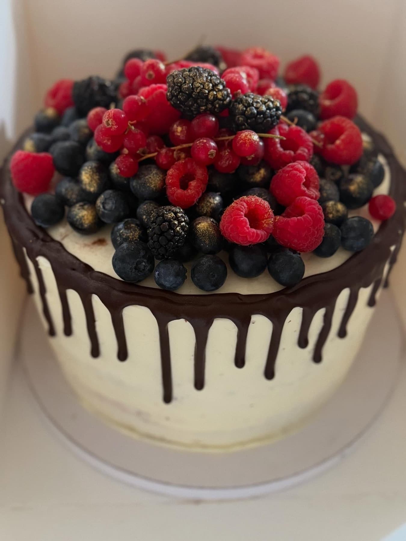 Torte mit dunklem Schokoladendrip und frischen Himbeeren und Brombeeren
