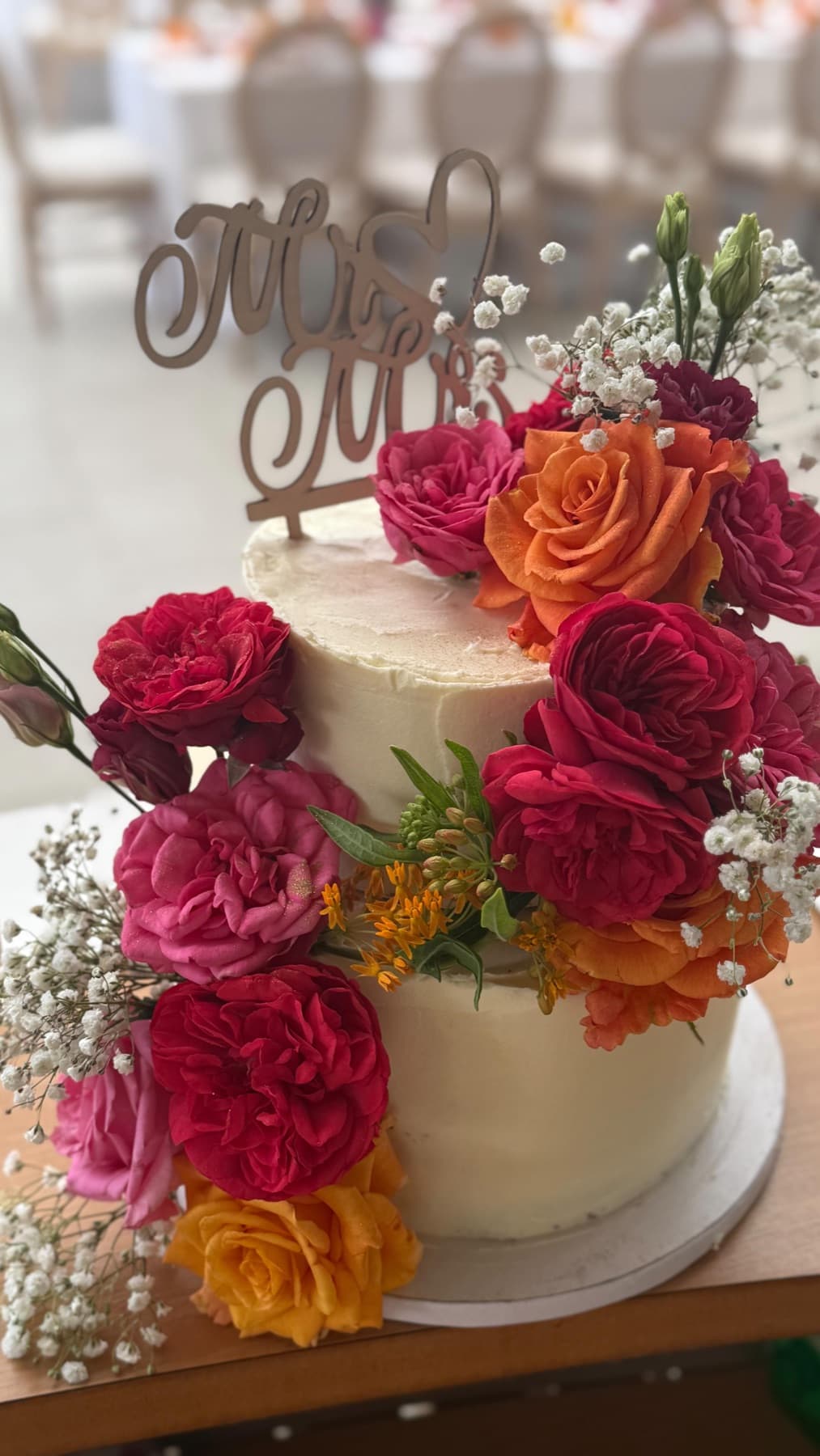 Hochzeitstorte mit kräftigen roten und orangen Rosen und Schleierkraut