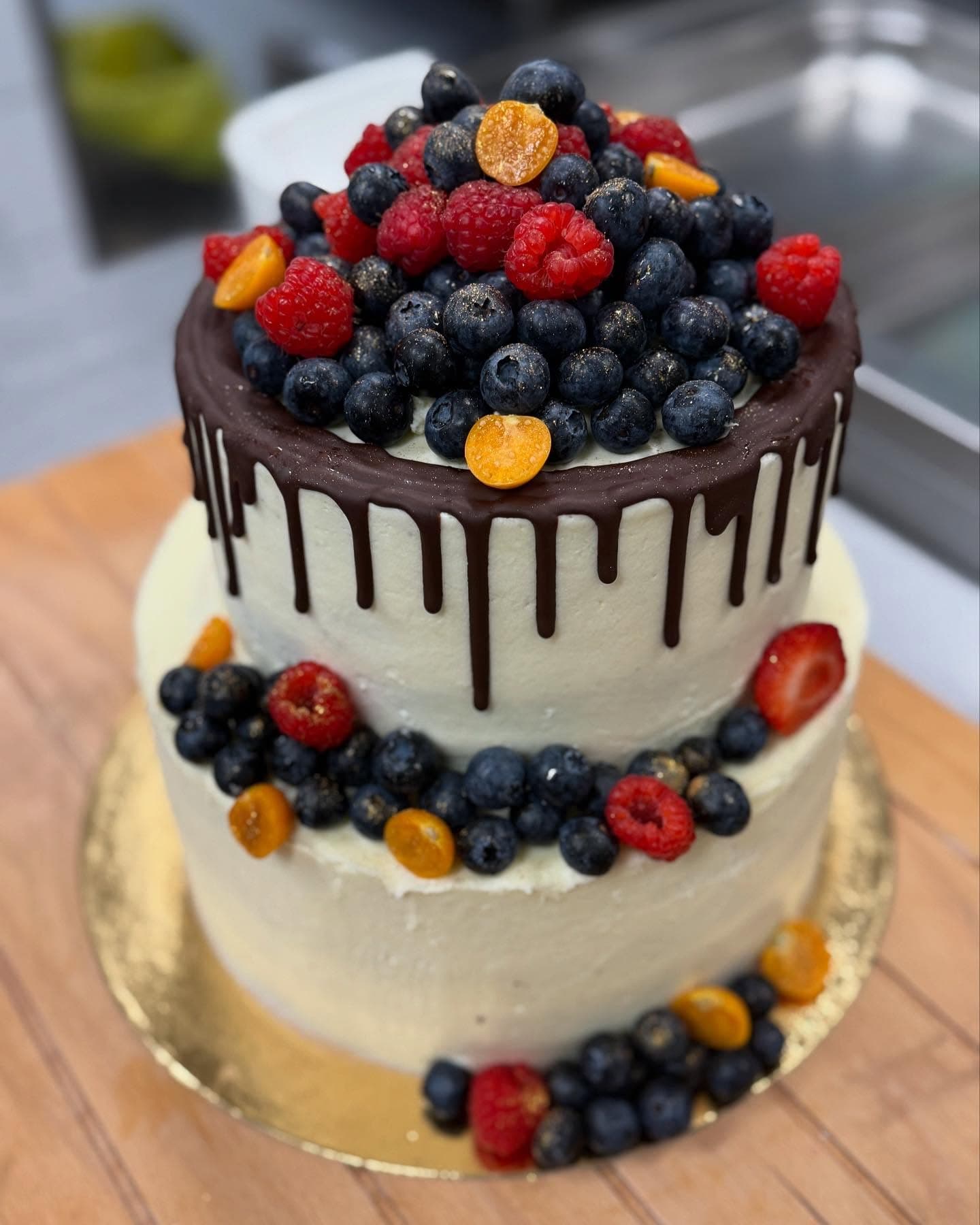 Zweistöckige Torte mit Schokoladendrip, Beeren und Physalis