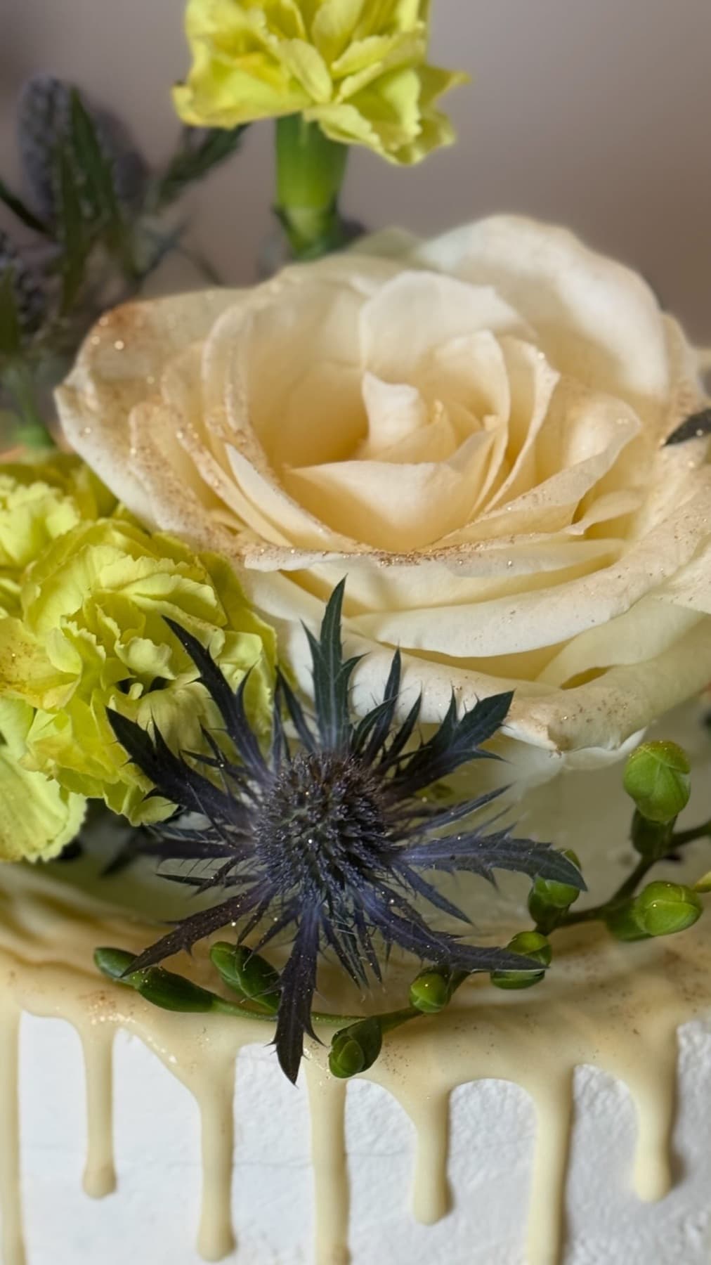 Nahaufnahme einer cremefarbenen Rose und Distel auf einer Torte
